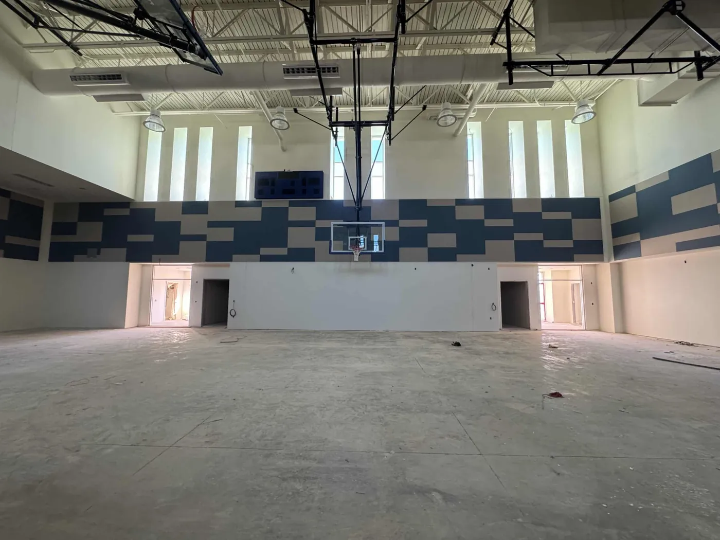 Custom acoustic wall panels being installed in a large gymnasium