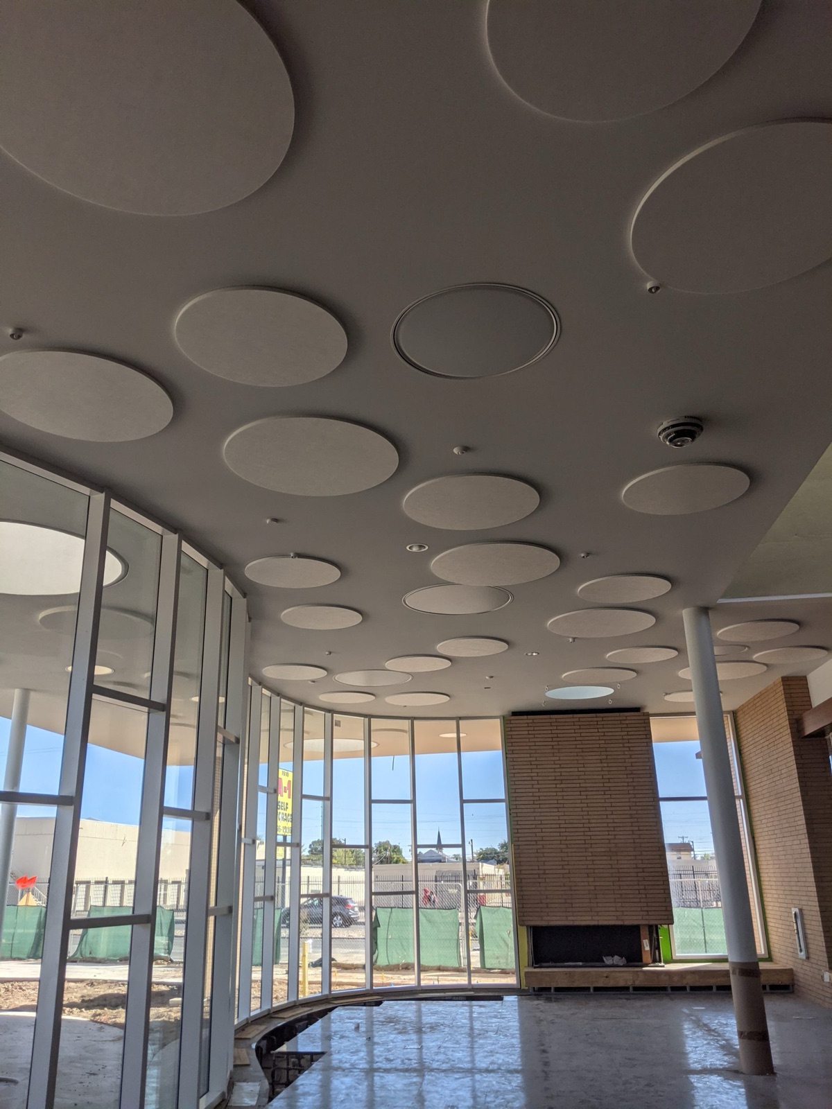 Circular acoustic ceiling panels arranged above a finished commercial interior