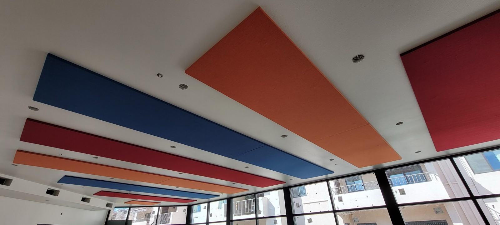 Blue, red and orange acoustic panels integrated across a ceiling
