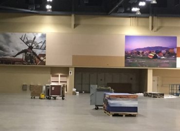 Neutral acoustic panels beneath landscape images in a large gathering space.