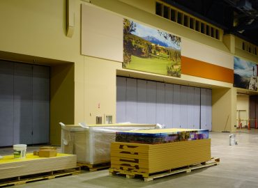 Warm-toned acoustic wall treatment around a service area and large graphics.