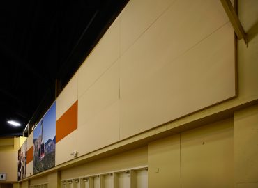 Large neutral acoustic wall panels above a public concourse.