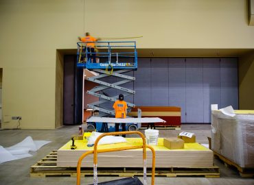 Installer on a lift working within a large gray wall-panel opening.