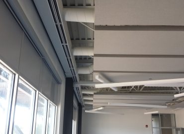 Gray suspended ceiling baffles positioned above windows.