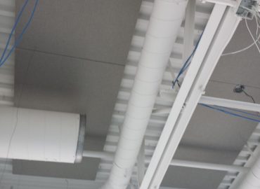 Close view of gray ceiling baffles around exposed ductwork.