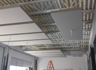 Multiple gray suspended ceiling clouds in a room under construction.