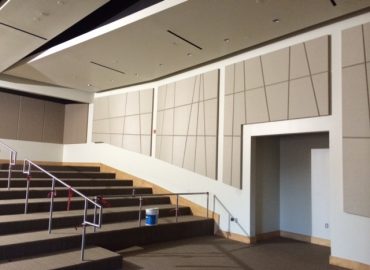 Gray geometric wall panels along a tiered auditorium.