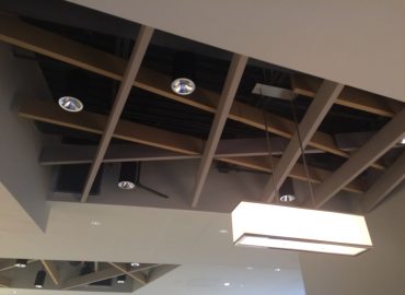 Deep coffered ceiling with integrated acoustic elements and pendant lights.