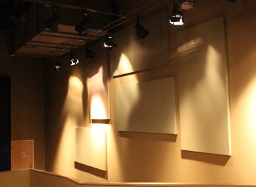 Light-colored acoustic panels arranged beside a performance stage.