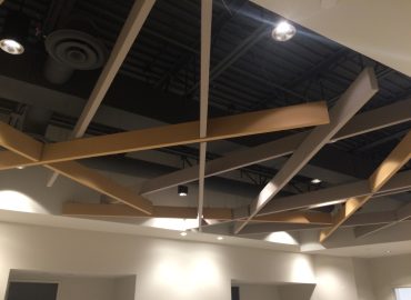 Geometric suspended baffles crossing below an exposed dark ceiling.