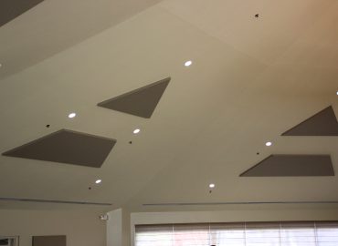 Triangular gray acoustic panels integrated into a white ceiling.