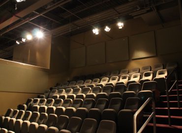 Dark acoustic wall panels surrounding tiered theater seating.
