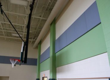 Blue and green acoustic panels around a gym wall and windows.
