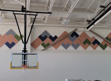Wide gym wall with custom chevron panels and basketball hoop.