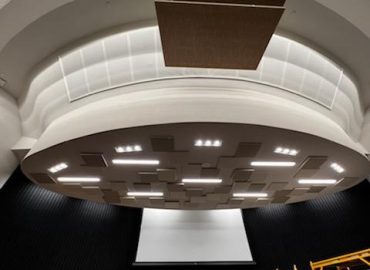 Circular acoustic ceiling feature above a stage or auditorium.